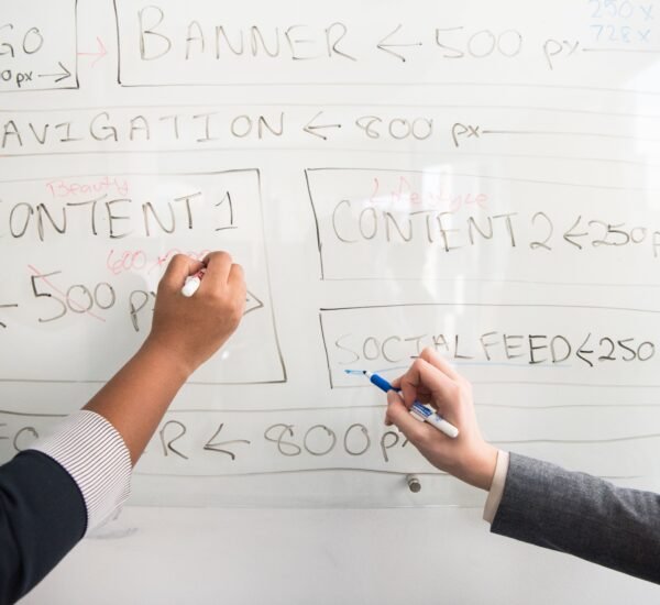 Two people planning a workflow on a whiteboard, representing how to build an AI workflow without coding